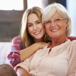Grandmother With Adult Granddaughter Relaxing On Sofa